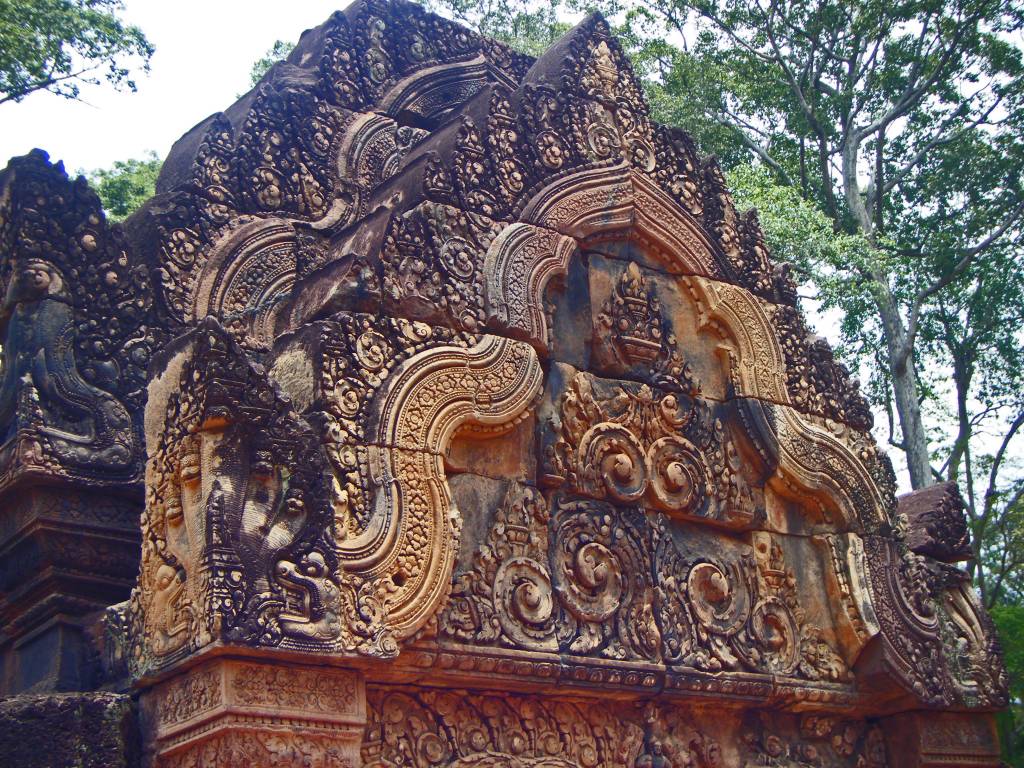 A close-up of the intricately carved pink sandstone walls of Banteay Srei temple in Angkor, Cambodia