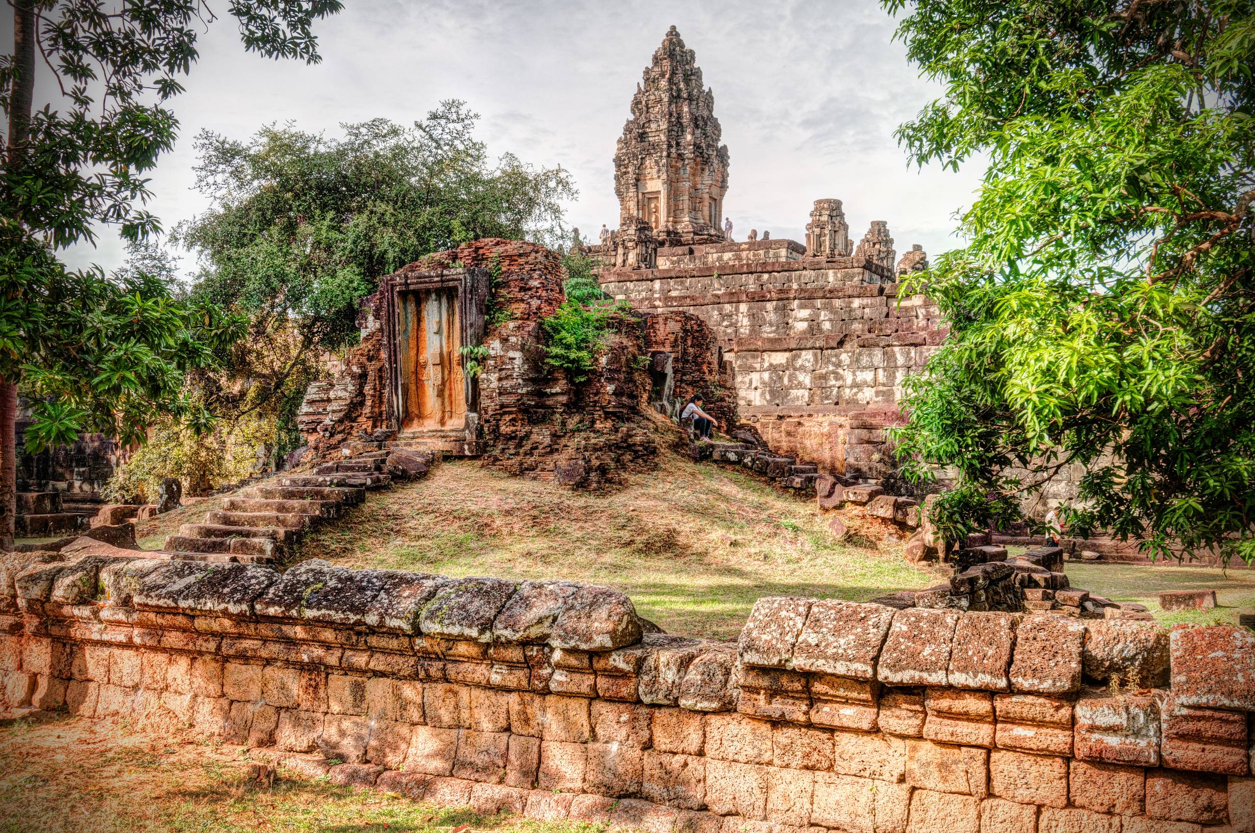A photo of the Roluos Group of temples, located in a remote area of Angkor, featuring intricate stone carvings and towering spires.